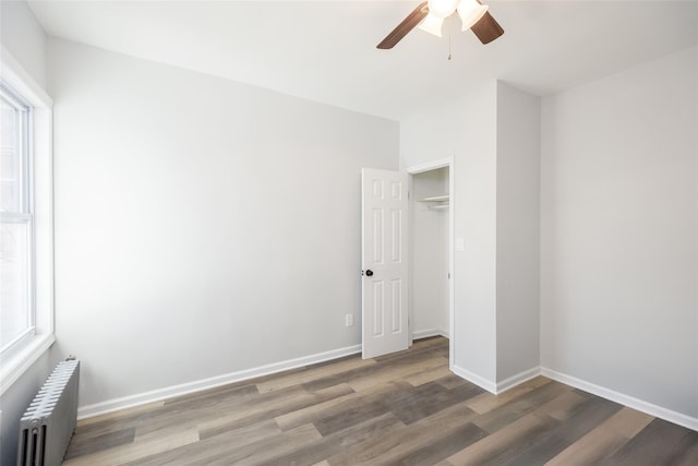 unfurnished bedroom with baseboards, ceiling fan, wood finished floors, and radiator