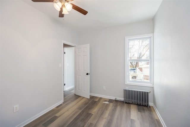 unfurnished room featuring baseboards, a ceiling fan, radiator, and wood finished floors