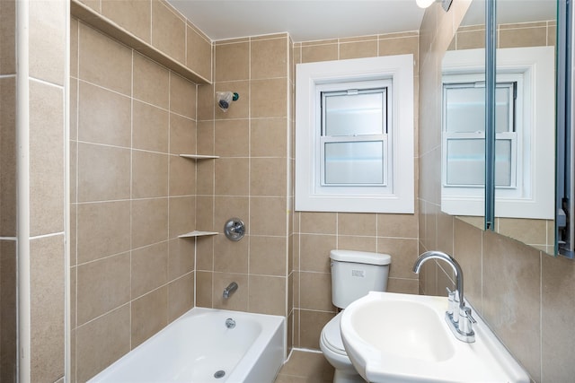 bathroom featuring a sink, shower / washtub combination, toilet, and tile walls