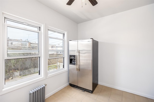interior space with radiator, baseboards, a wealth of natural light, and stainless steel fridge with ice dispenser