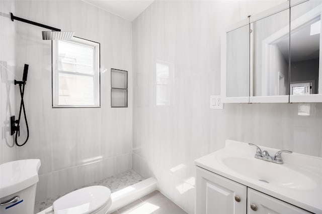 bathroom featuring toilet, a tile shower, and vanity