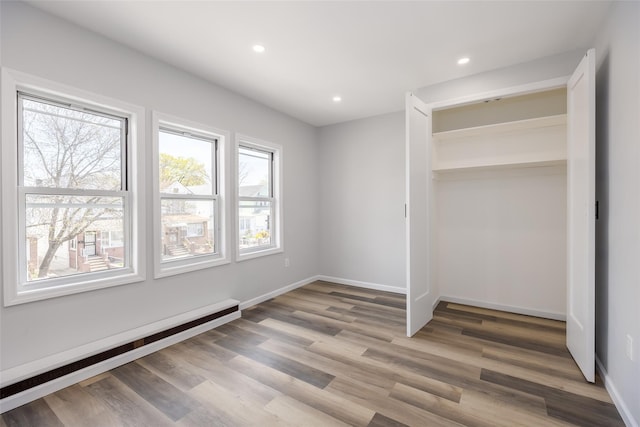 unfurnished bedroom featuring recessed lighting, baseboards, a baseboard radiator, and light wood finished floors