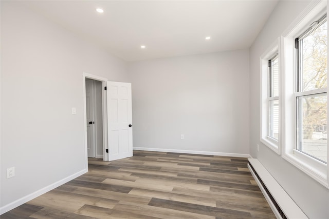 unfurnished room with recessed lighting, baseboards, wood finished floors, and a baseboard radiator