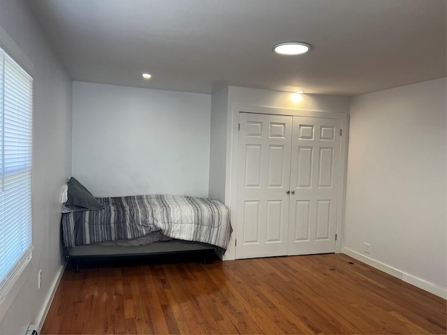 bedroom with baseboards, multiple windows, and wood finished floors