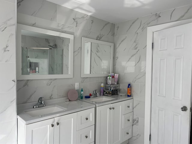 bathroom featuring a sink, tile walls, double vanity, and a marble finish shower