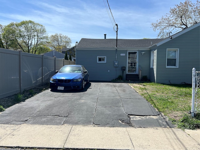 view of front of house featuring a front yard, fence, a shingled roof, and entry steps