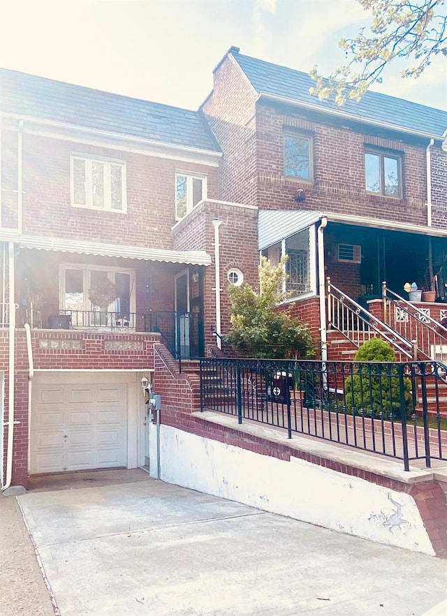 view of front of home featuring driveway, a garage, brick siding, fence, and stairs