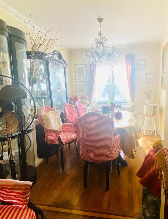 dining space with crown molding, wood finished floors, and a chandelier
