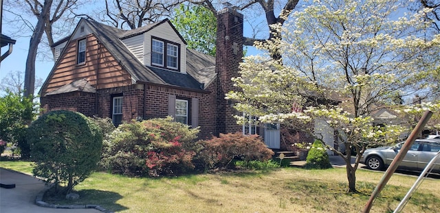view of front of house featuring brick siding, a shingled roof, and a front yard