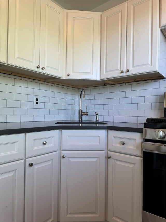91 Tulip Ave Unit C2, Floral Park, NY 11001 - kitchen with decorative backsplash, dark countertops, stainless steel gas range oven, a sink, and white cabinetry