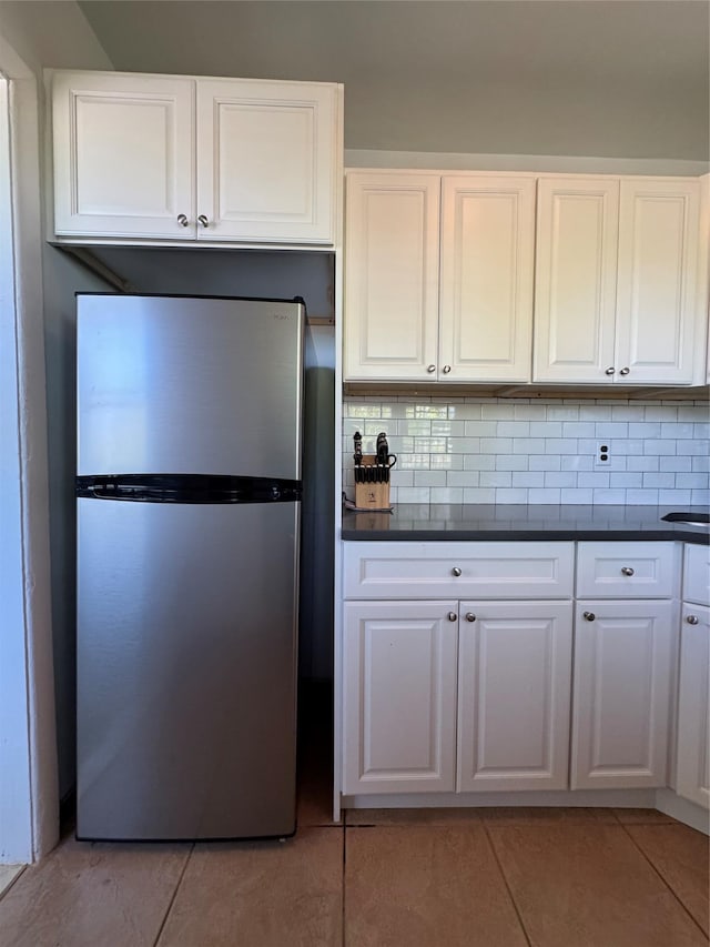 91 Tulip Ave Unit C2, Floral Park, NY 11001 - kitchen featuring freestanding refrigerator, dark countertops, light tile patterned floors, and tasteful backsplash