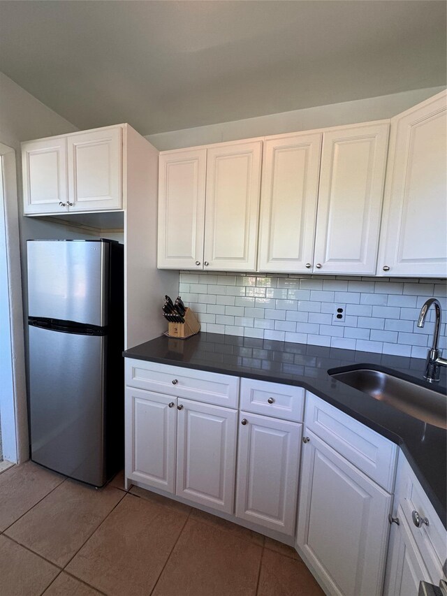 91 Tulip Ave Unit C2, Floral Park, NY 11001 - kitchen with backsplash, dark countertops, a sink, freestanding refrigerator, and white cabinetry