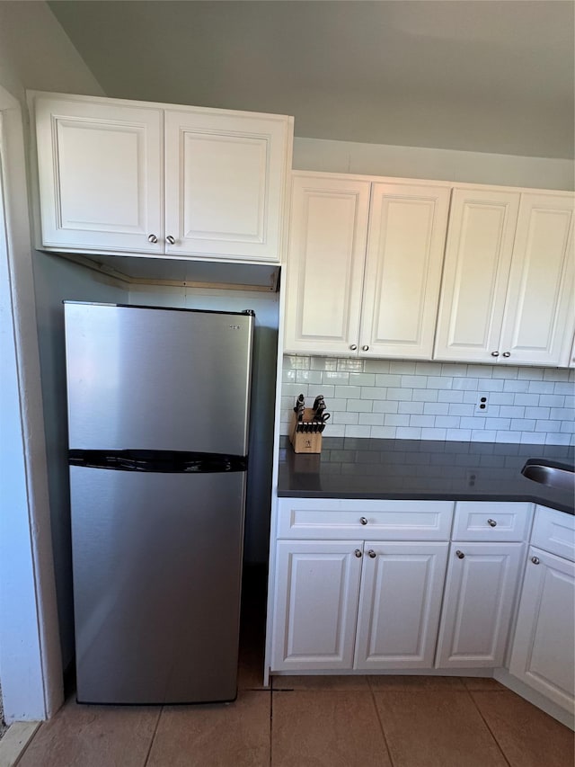 91 Tulip Ave Unit C2, Floral Park, NY 11001 - kitchen with freestanding refrigerator, backsplash, dark countertops, and light tile patterned floors