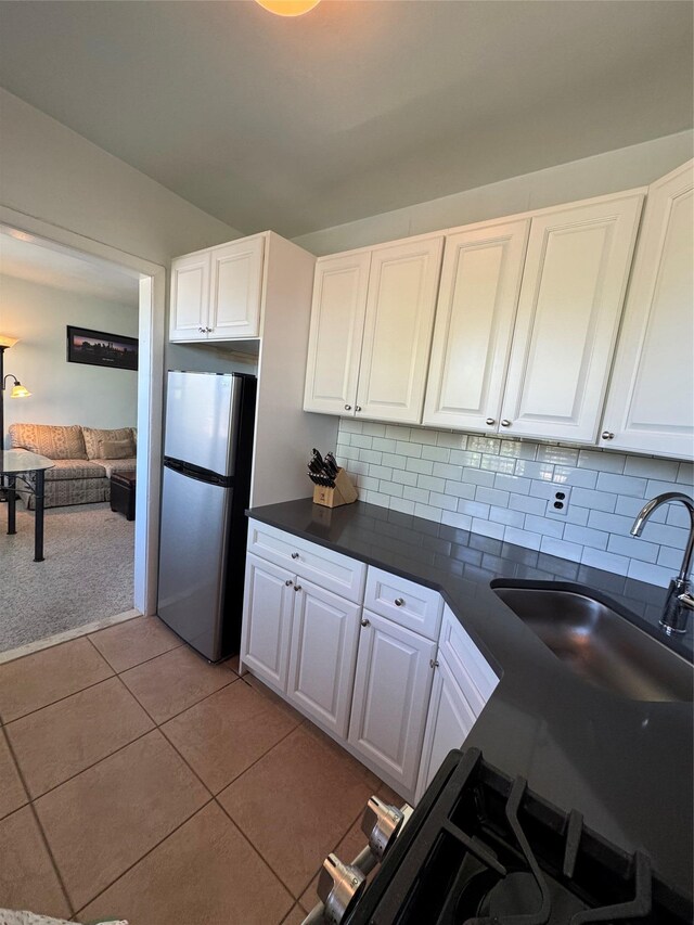 91 Tulip Ave Unit C2, Floral Park, NY 11001 - kitchen with decorative backsplash, dark countertops, light tile patterned floors, white cabinets, and freestanding refrigerator