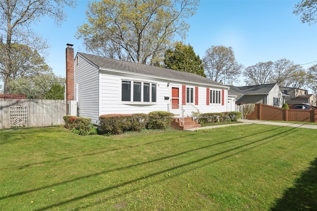 view of front facade with fence, a chimney, driveway, and a front lawn