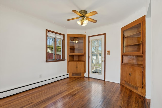 empty room featuring crown molding, ceiling fan, a baseboard heating unit, and hardwood / wood-style floors