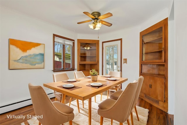 dining area with wood finished floors, a baseboard heating unit, and a healthy amount of sunlight