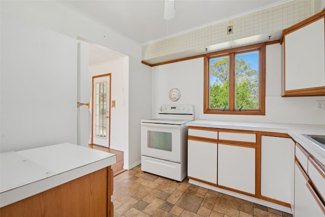 kitchen with light countertops, stone finish floor, white electric range oven, and white cabinetry