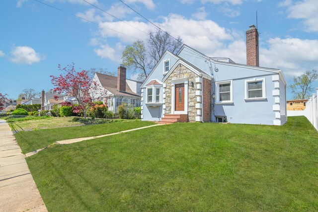 bungalow-style home featuring a chimney, stone siding, and a front lawn