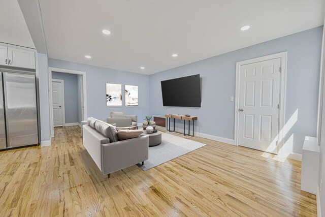 living area featuring light wood-style floors, baseboards, and recessed lighting