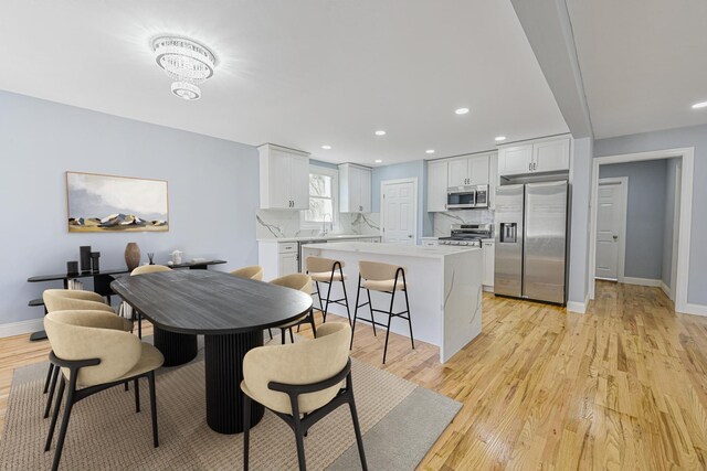 dining room with light wood-style floors, recessed lighting, and baseboards