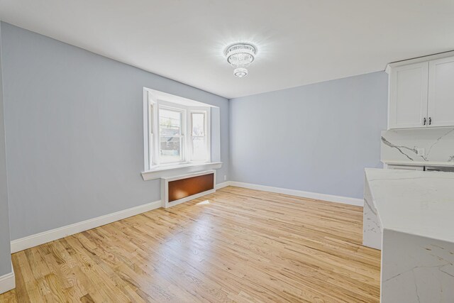 unfurnished dining area with light wood-style floors and baseboards
