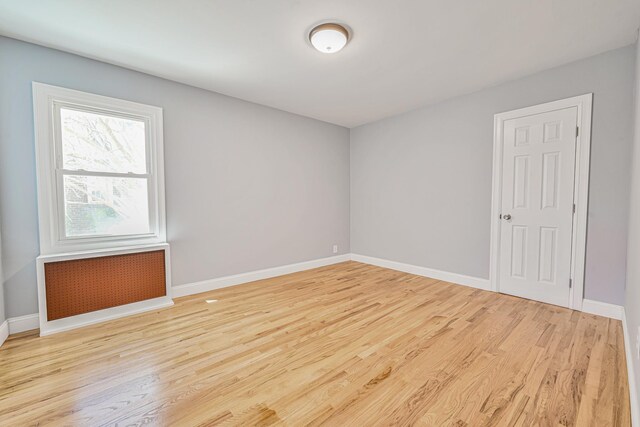 empty room featuring baseboards and light wood finished floors