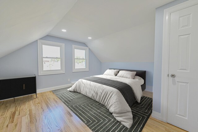 bedroom featuring baseboards, wood finished floors, and lofted ceiling