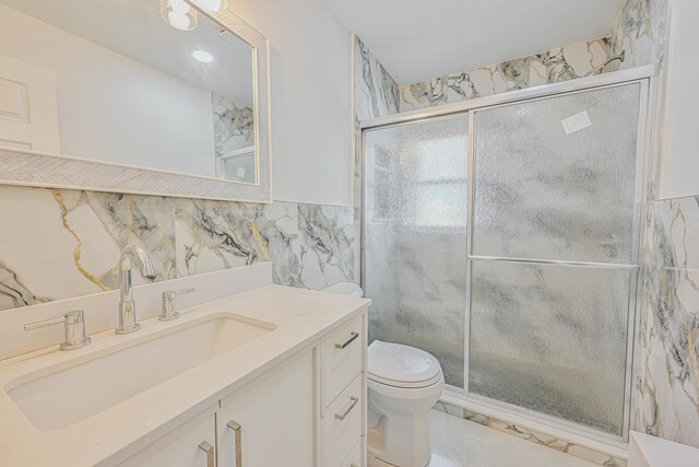 bathroom with vanity, marble finish floor, toilet, tile walls, and a shower stall
