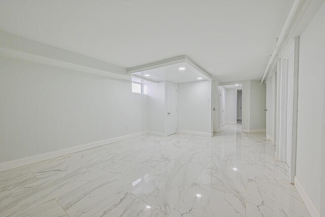 below grade area featuring baseboards, recessed lighting, and marble finish floor