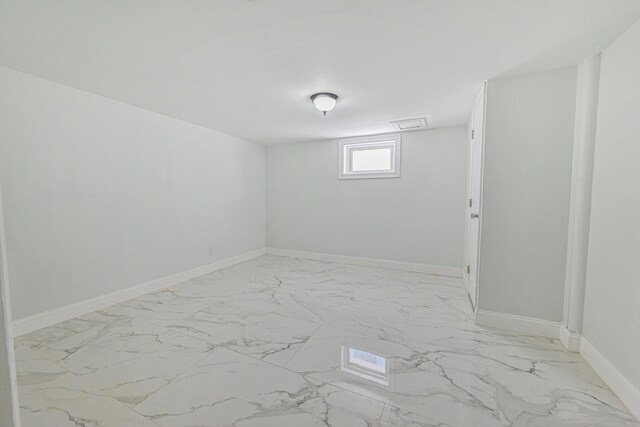basement with baseboards and marble finish floor