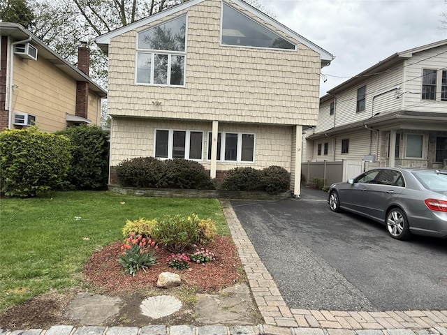 view of front of house featuring an AC wall unit, fence, and a front lawn