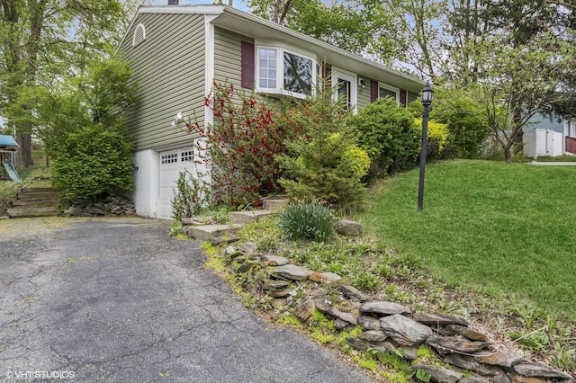 view of side of property featuring a chimney, a garage, a yard, and driveway