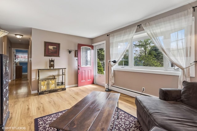 living area with baseboards, light wood-style floors, and a baseboard heating unit
