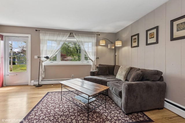 living area with plenty of natural light, a baseboard heating unit, and wood finished floors