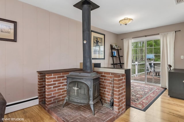interior details with baseboard heating, a wood stove, wood finished floors, and visible vents