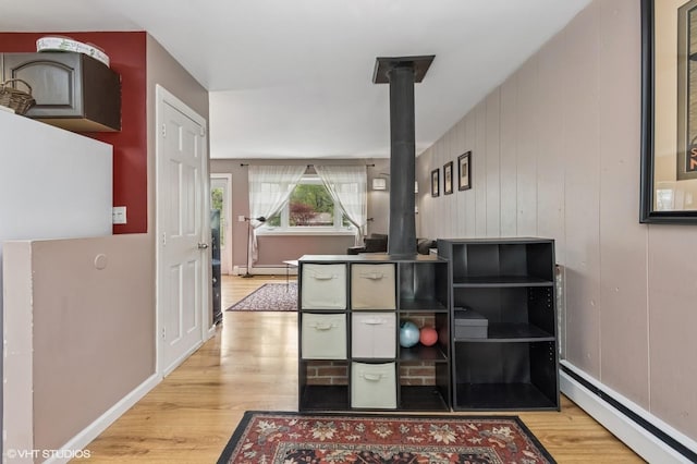 interior space featuring baseboards, a baseboard heating unit, wood finished floors, and a wood stove