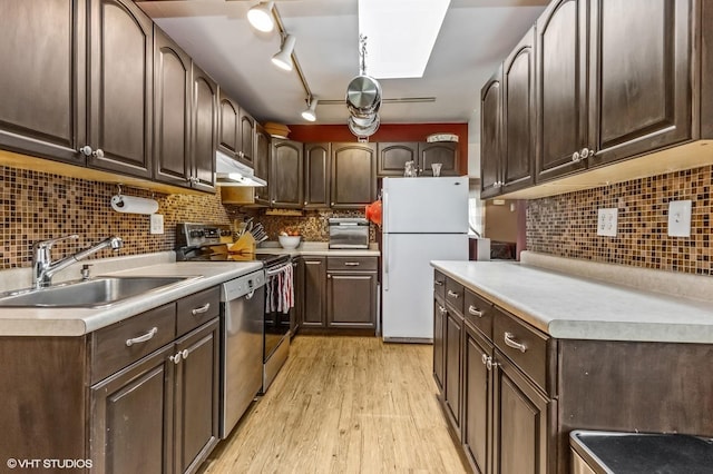 kitchen featuring dark brown cabinets, a sink, dishwasher, freestanding refrigerator, and under cabinet range hood