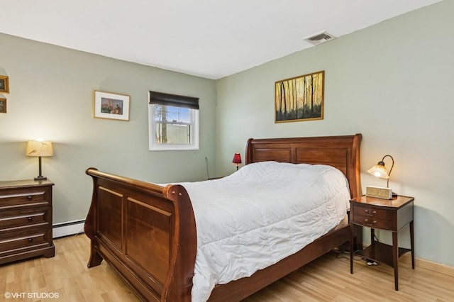 bedroom featuring visible vents, wood finished floors, and a baseboard radiator