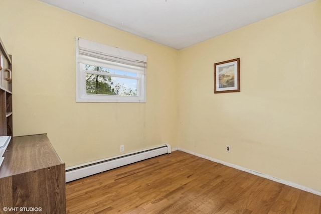 empty room with baseboards, a baseboard radiator, and wood finished floors