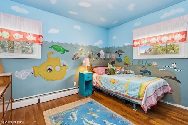bedroom featuring wood finished floors and a baseboard heating unit