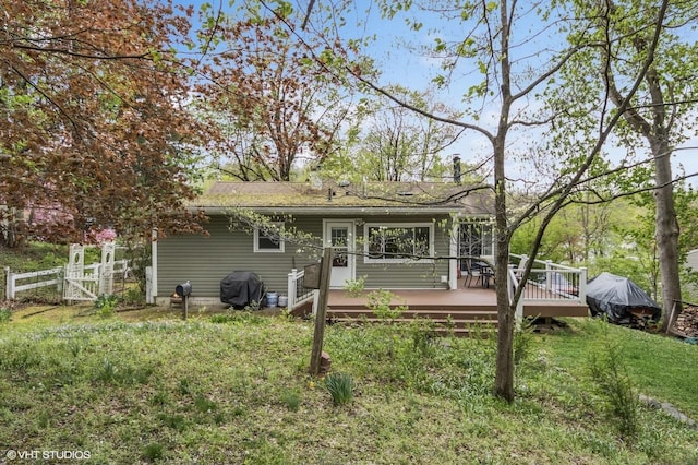 rear view of house featuring a yard, a deck, fence, and a gate