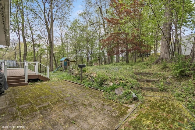 view of yard featuring a patio, a playground, and a wooden deck