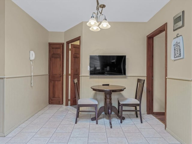 dining space featuring a wainscoted wall and a chandelier