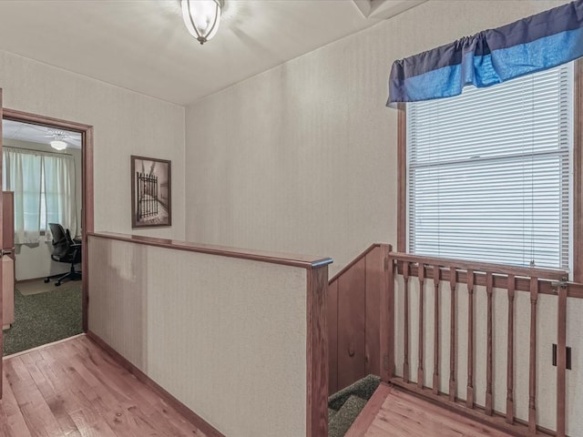 hallway featuring light wood finished floors and a desk