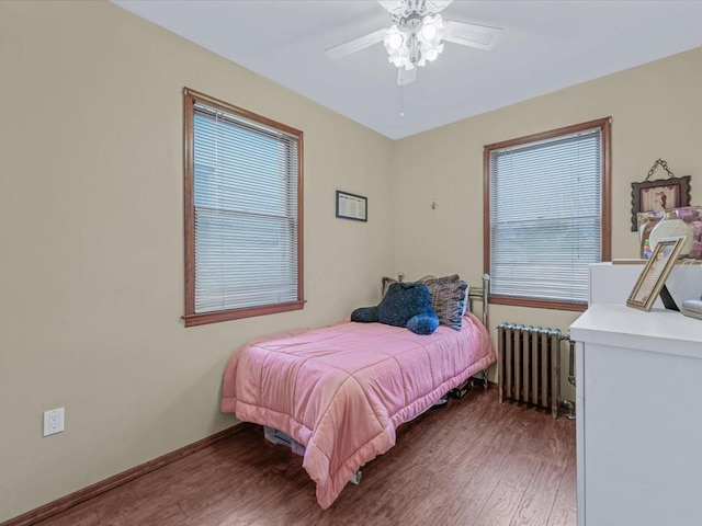 bedroom with radiator, wood finished floors, baseboards, and a ceiling fan
