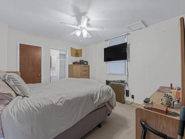 bedroom with light carpet, attic access, a ceiling fan, radiator, and ensuite bath