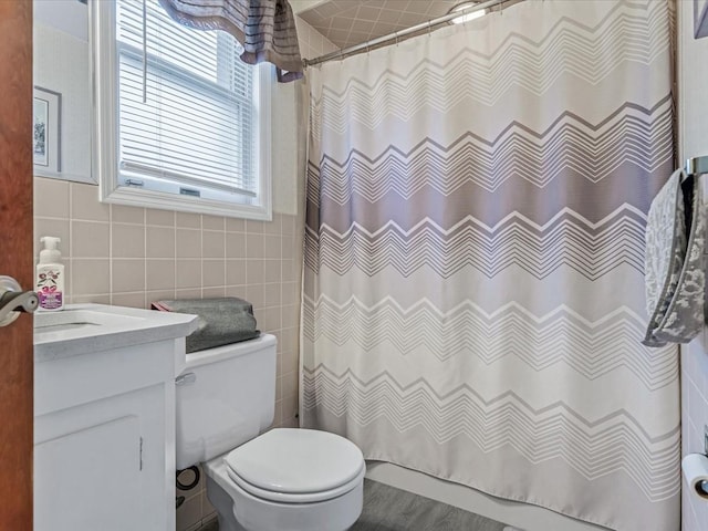full bath with tile walls, toilet, vanity, and a shower with curtain