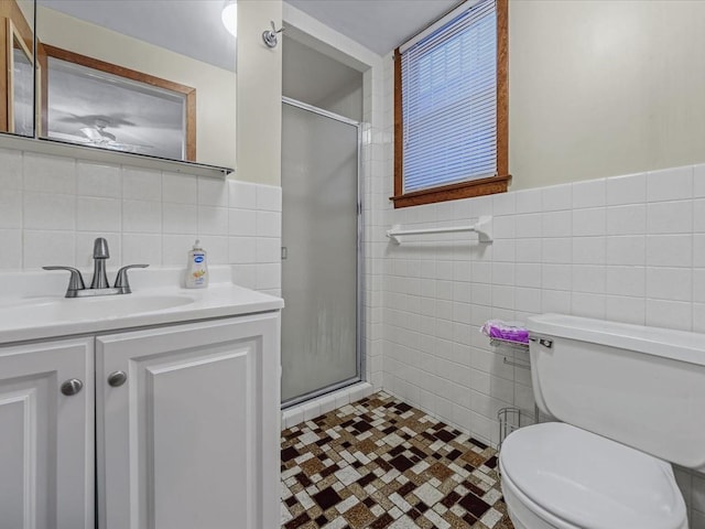 bathroom featuring tile walls, a shower stall, toilet, and vanity