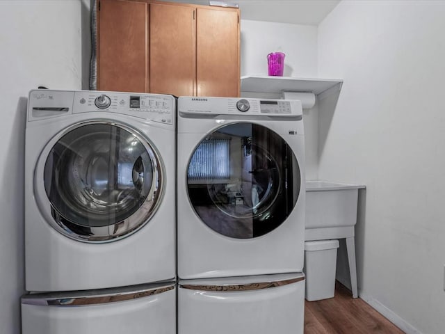 washroom with washer and clothes dryer, cabinet space, wood finished floors, and baseboards